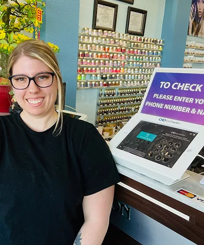 Salon customer using Go Check In tablet at nail salon front desk